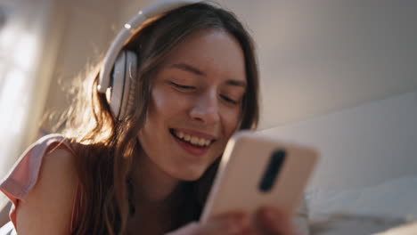 carefree girl listening headphones music closeup. smiling woman browsing mobile