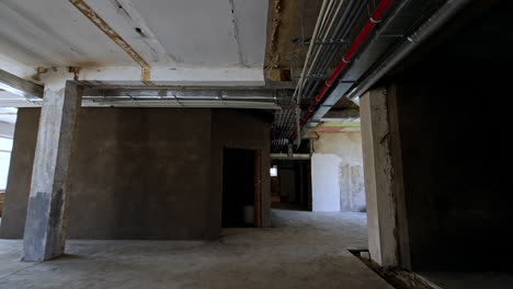inside the spacious room with unfinished walls, ceiling and floor. low angle view at the pipes on the ceiling of the premise. renovation concept.