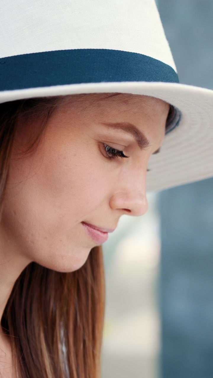 Una bella donna che indossa un cappello bianco con una fascia blu, ripresa in uno scatto verticale.