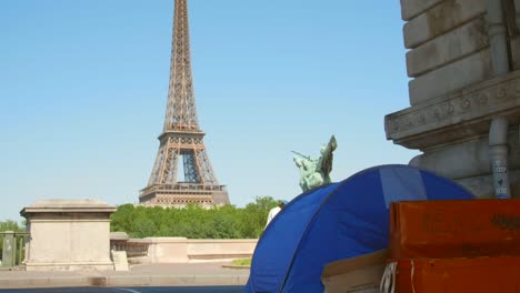 homeless tent under the bir hakeim bridge overlooking eiffel tower in paris, france