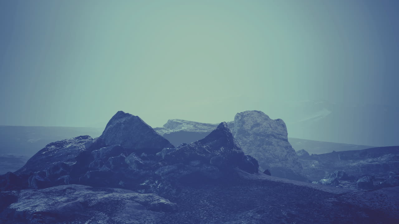 Landscape of rugged rocks under misty sky with soft blue tones at twilight