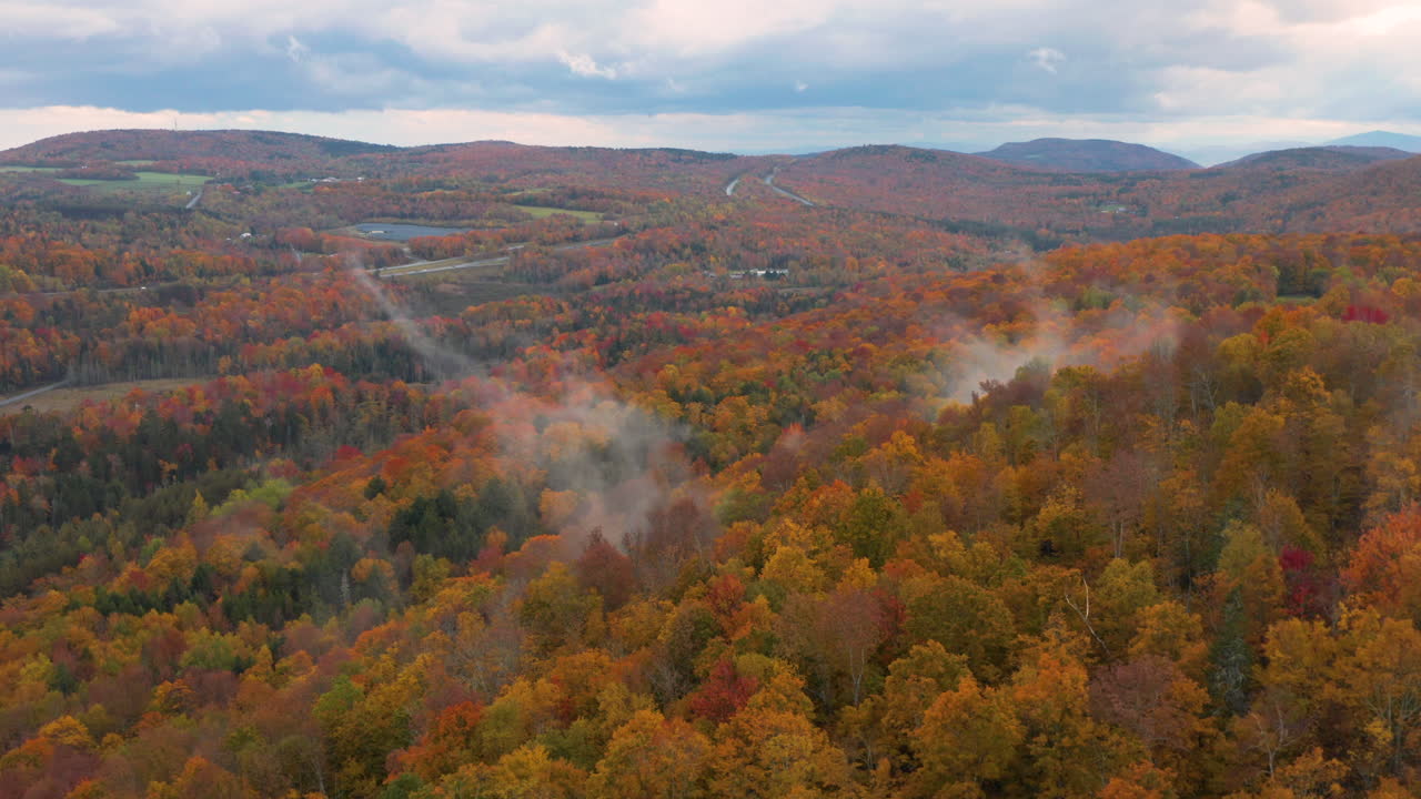 toma aérea sobrevolando viendo la niebla subir desde las coloridas colinas en vermont, nueva inglaterra en el otoño