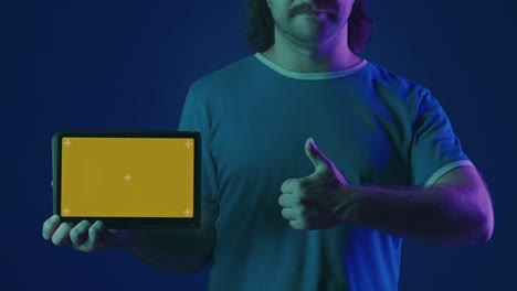 man holding a tablet with a blank screen in neon lighting.