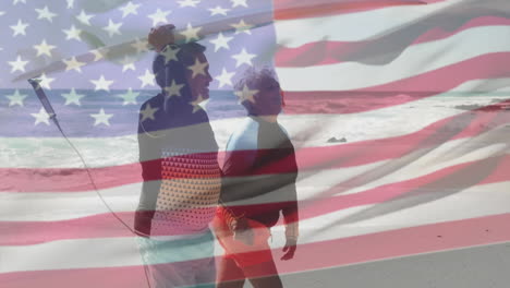 animación de la bandera de los estados unidos de américa sobre una pareja biracial mayor con tablas de surf en la playa