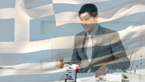 waving greece flag against caucasian young businessman celebrating at office