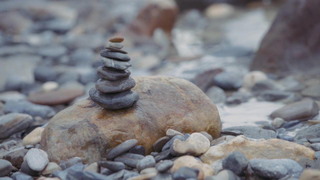 Balanced stones stacked on the big rock near the river