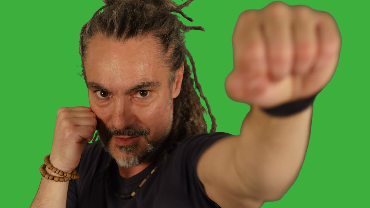 artista marcial haciendo entrenamiento de lucha aislado en el fondo de la pantalla verde. enérgico hombre rasta de mediana edad boxeando contra la cámara.