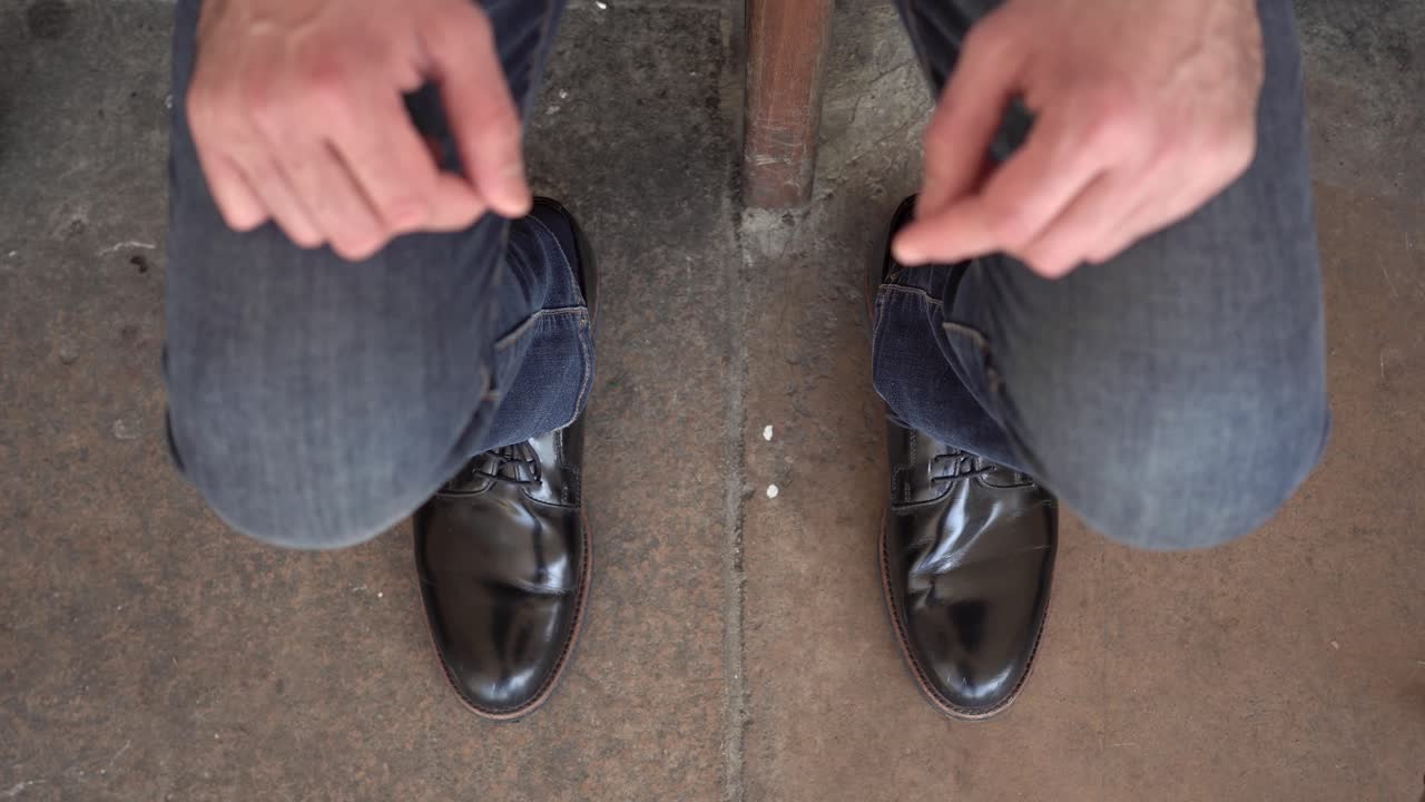A young man is tossing the cigarette stub away with his black shoe.He is against smoking. He can't stand cigarette
