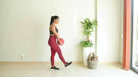 atleta étnico inclinado hacia adelante con una pelota de fitness en la habitación