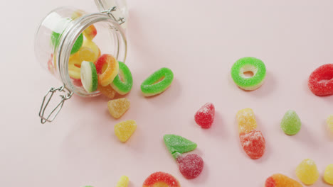 video of colourful jelly candy and jar on pink background