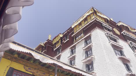 low angle of potala palace reveals rich colors and ornate detailing under blue sky, slow pan right