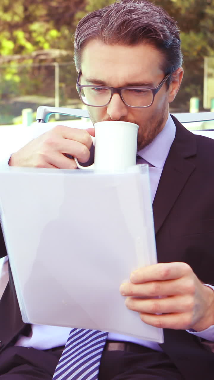 hombre de negocios guapo bebiendo café y leyendo documentos