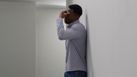 young businessman in office looking at message with bad news on mobile phone and leans against wall looking unhappy and depressed 1