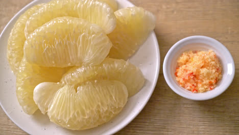 fresh peeled pomelo, grapefruit or shaddock on white plate