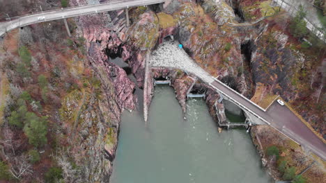 Forward-Moving-Aerial-Footage-of-Olidan-Hydroelectric-Power-Station-with-vehicle-crossing-over-the-corniche-cliffside-Oskarsbron-Oskar-bridge-at-Trollhättan-waterfalls-and-locks-in-Sweden