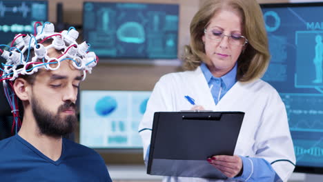 doctora que toma notas mientras el paciente lleva sensores cerebrales