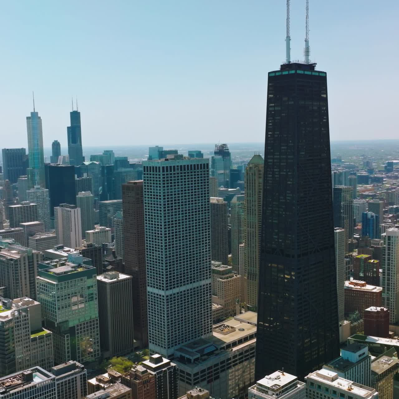 High dark skyscraper standing out among the other architecture. Drone footage over the stunning Chicago at sunny day