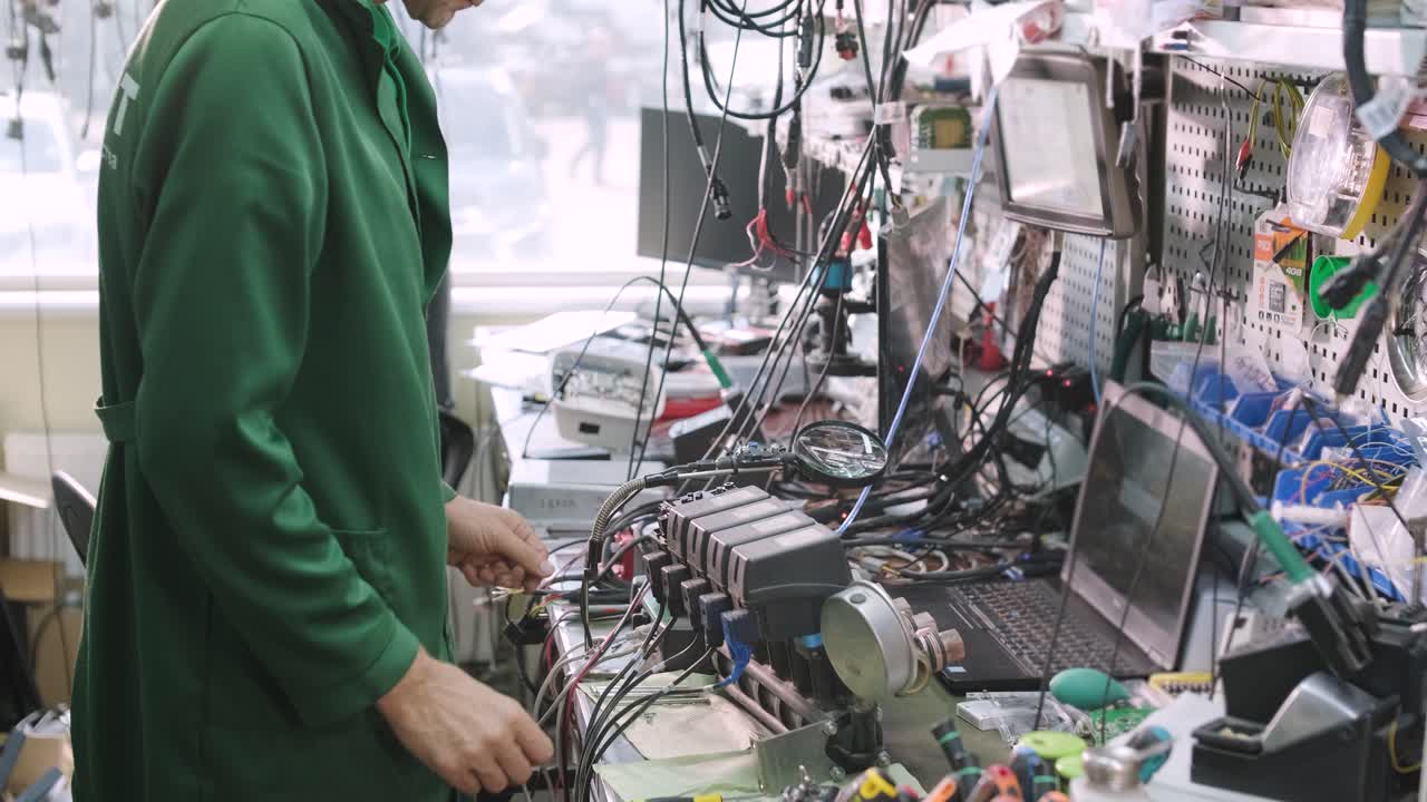 tienda de reparación de equipos electrónicos. el técnico ingeniero soldada la placa de circuitos impresos de un dispositivo electrónico bajo un microscopio.