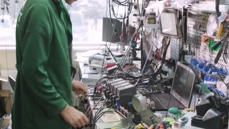 tienda de reparación de equipos electrónicos. el técnico ingeniero soldada la placa de circuitos impresos de un dispositivo electrónico bajo un microscopio.