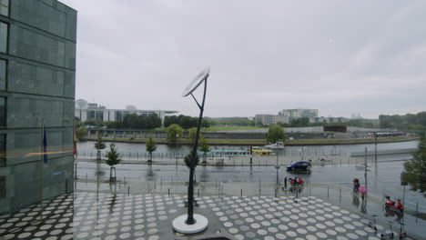 wide shot of the front of futurium with circle pavement and river spree with moving boat in berlin, germany, rainy day