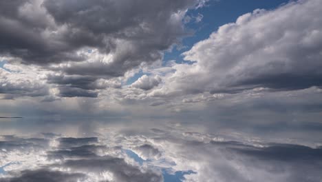 futuristic background consisting of time lapse clip of white fluffy clouds over blue sky and their reflection, video loop