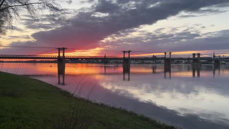 river loire slowly moving under an old bridge with red sunset behind