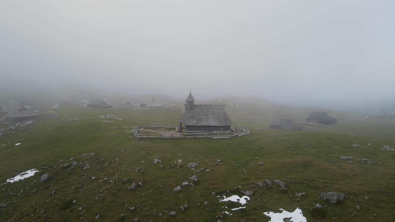 Luftfoto af kapel i tåge på grøn bakke med naturskøn udsigt, Kamnik, Slovenien