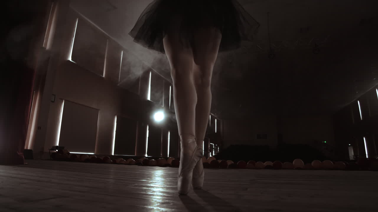 un primer plano de las piernas de la bailarina. ella baila con sus zapatillas de ballet. ella lleva un vestido de tutu negro. filmado en un estudio brillante y soleado. en cámara lenta.