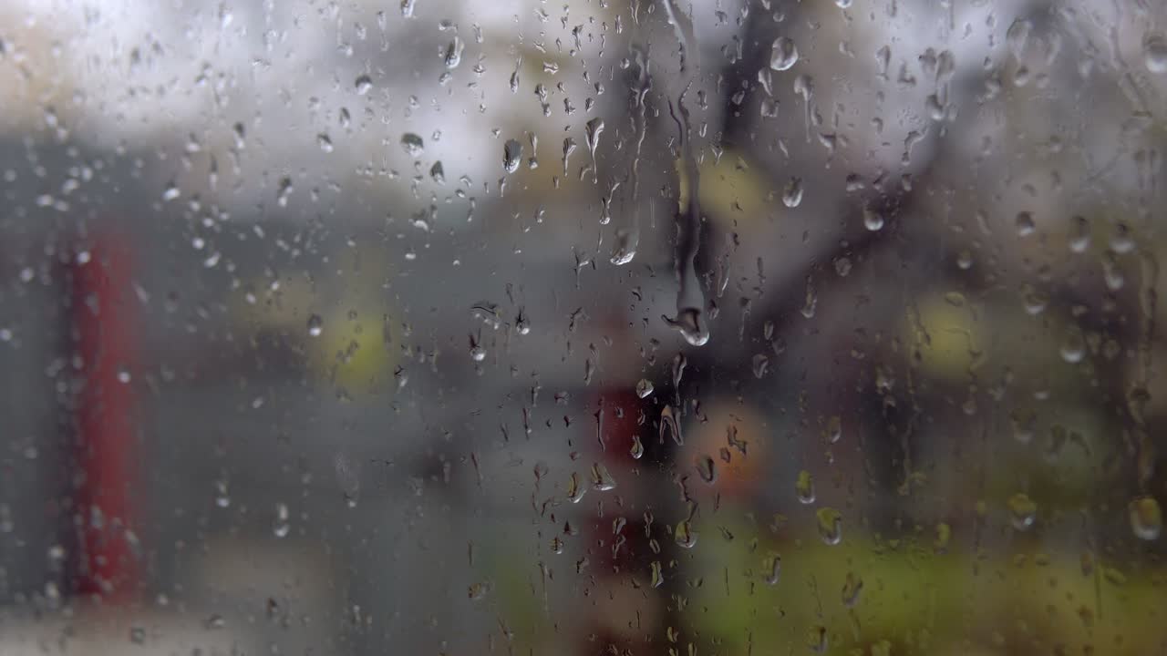 Cloudy weather and rain outside the window. Wet and misted window with dripping rain gums close up