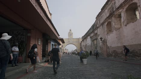 fast pan down of the famous arch in antigua, guatemala with people walking down the road