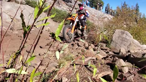 a dirt bike racer makes his way down a rocky path