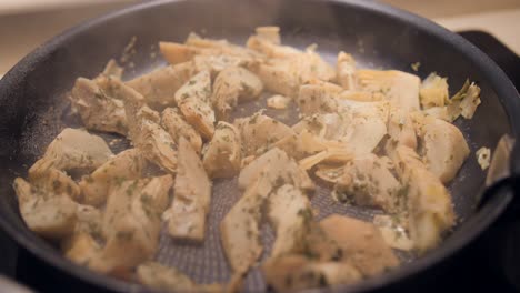salteado de alcachofas cocinando en la sartén, comida típica en españa