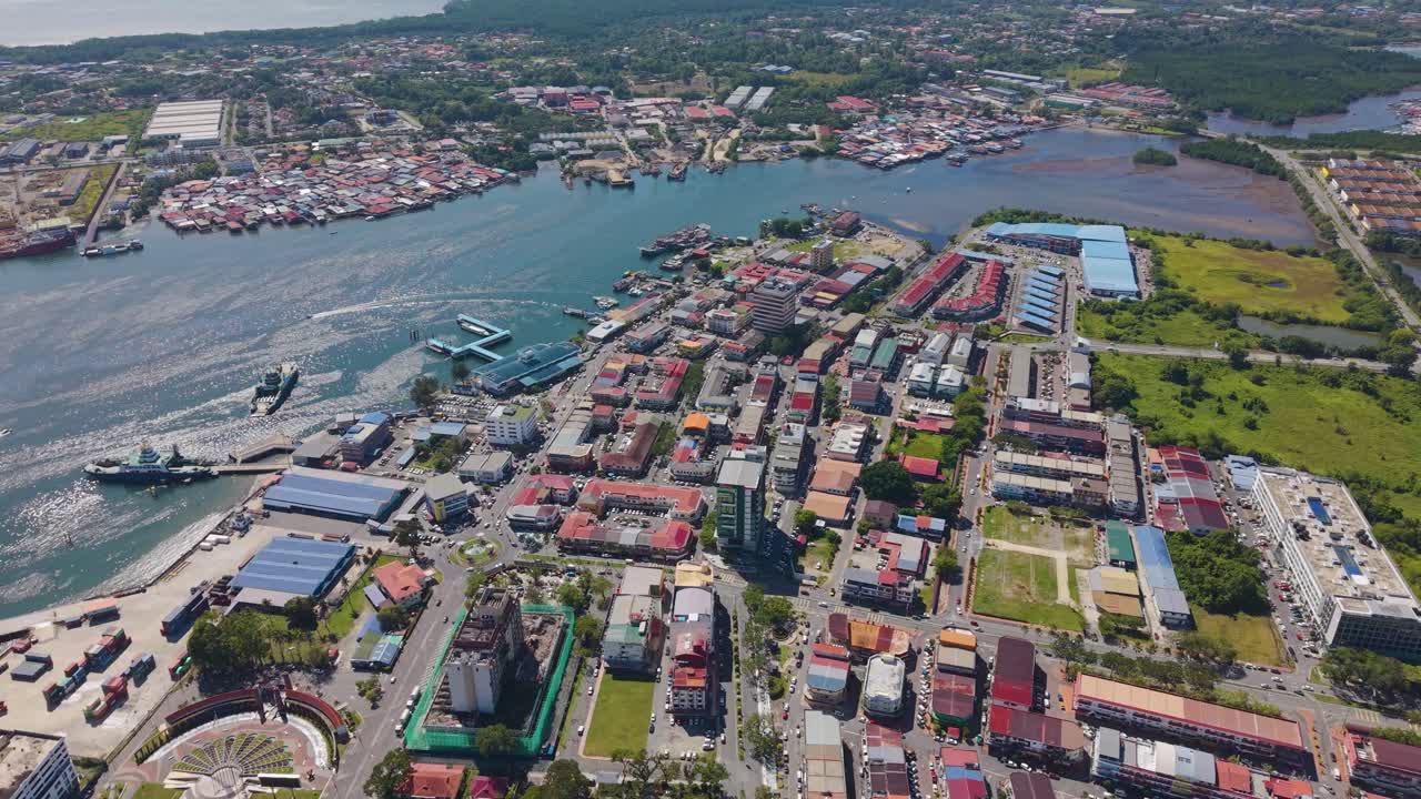 Pull in drone shot of Victoria cityscape in Labuan, Malaysia, showcasing coastal urban life, waterways, and vibrant architecture under bright tropical sunlight