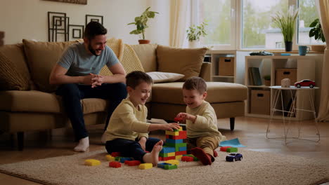 father and sons playing with building blocks at home