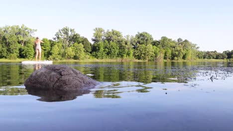 young couple paddle boarding on sups along a calm blue lake