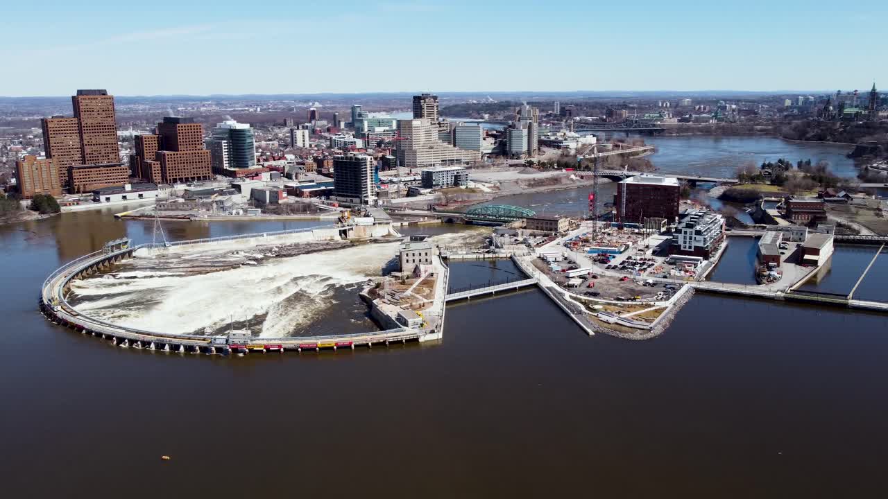 Aerial view flying around an electric dam with Gatineau and Ottawa parliament in the background