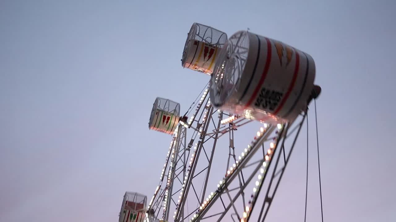 A carnival ferris wheel spins while the camera zooms out and tilts up.