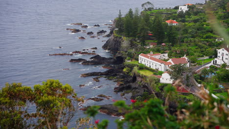 high view of local town located on top of rocky coastline surrounded by green lush vegetation