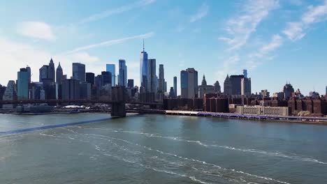 a pan shot of the new york skyline from the manhattan bridge over looking the east river and brooklyn bridge and manhattan
