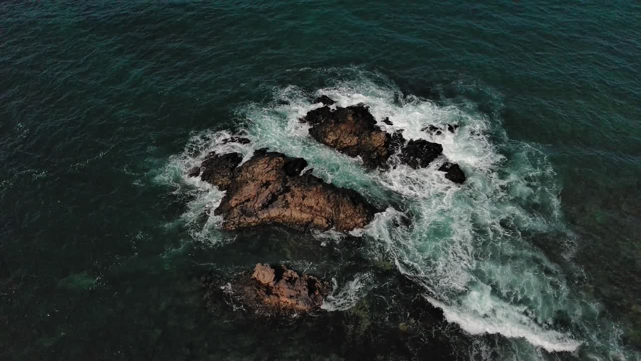 Pietre affilate circondate dalla schiuma del mare. Veduta aerea dall'alto.