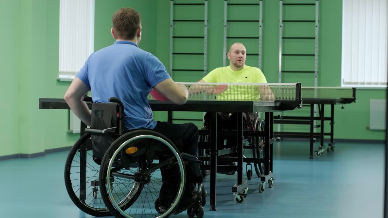un hombre en silla de ruedas juega ping pong. personas con discapacidad juegan tenis de mesa. rehabilitación de discapacitados. deporte paralímpico.