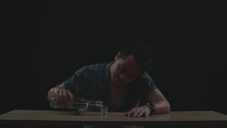 drunk asian man cheering vodka glass to camera before drinking in black background