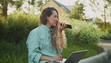 Woman-Recording-Voice-Message-and-Working-on-Laptop-on-Street