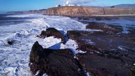 drone truck left over crashing waves and rocks at mavericks beach, california during sunset