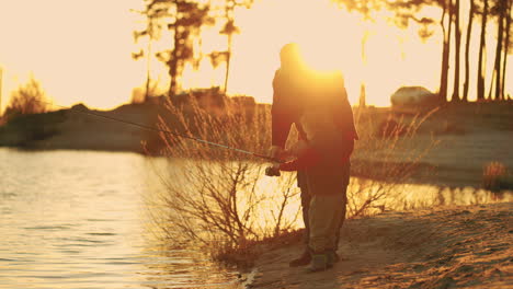 Ruhe-Am-Ufer-Des-Sees-Im-Sonnenuntergang.-Alter-Fischer-Und-Kleiner-Enkel-Angeln-Im-Fluss.-Glückliche-Kindheit