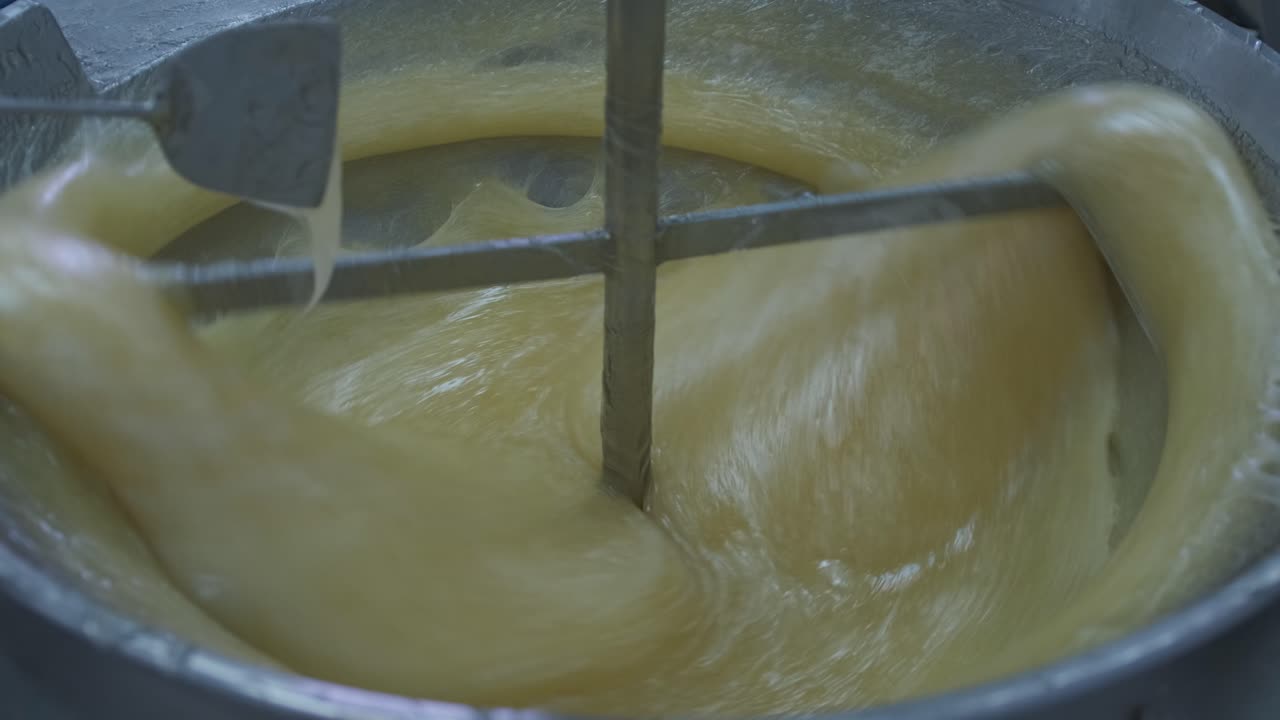 primer plano de una delicia turca que se está haciendo en una fábrica mientras un trabajador usa una espátula para probar el grosor