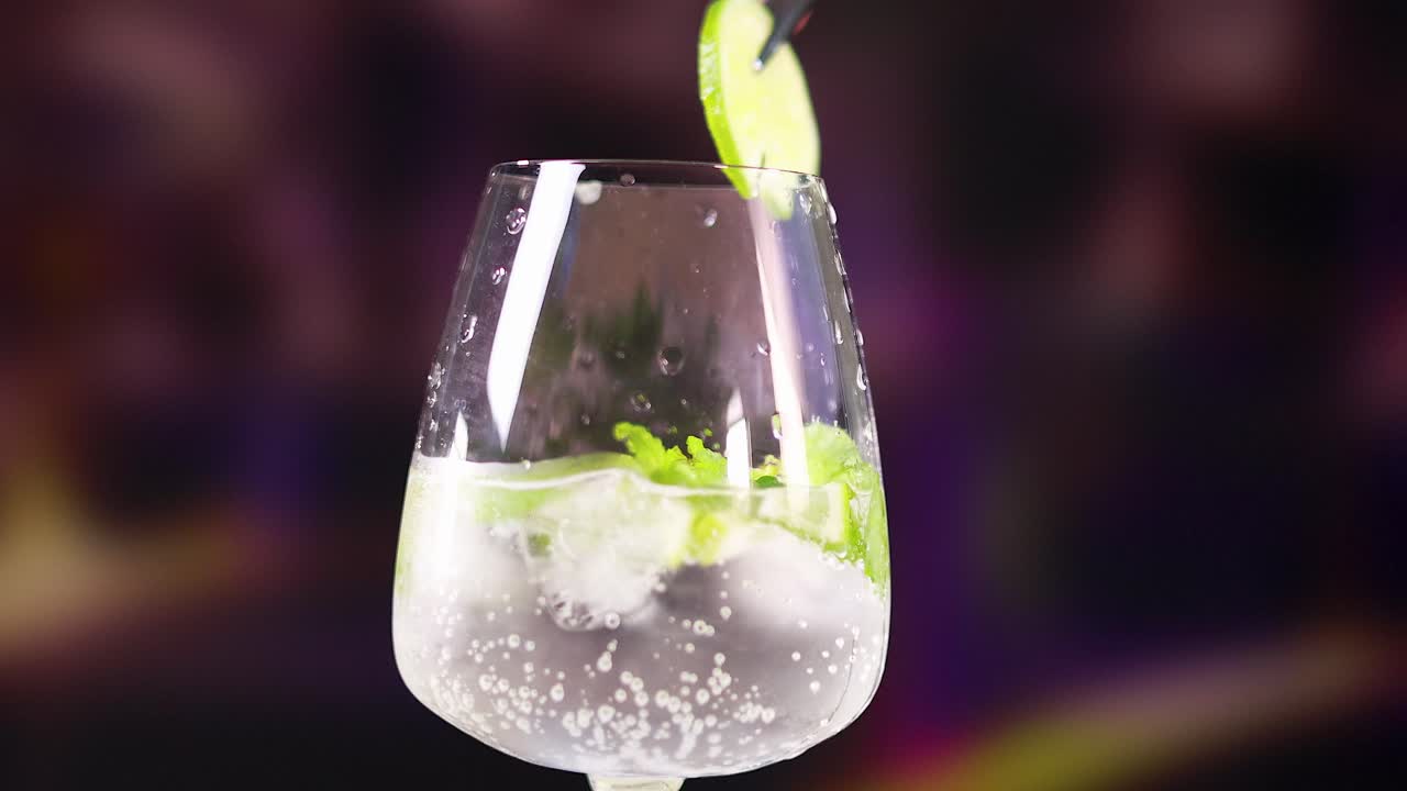 A sparkling mojito cocktail garnished with lime and mint in a vibrant, colorful setting