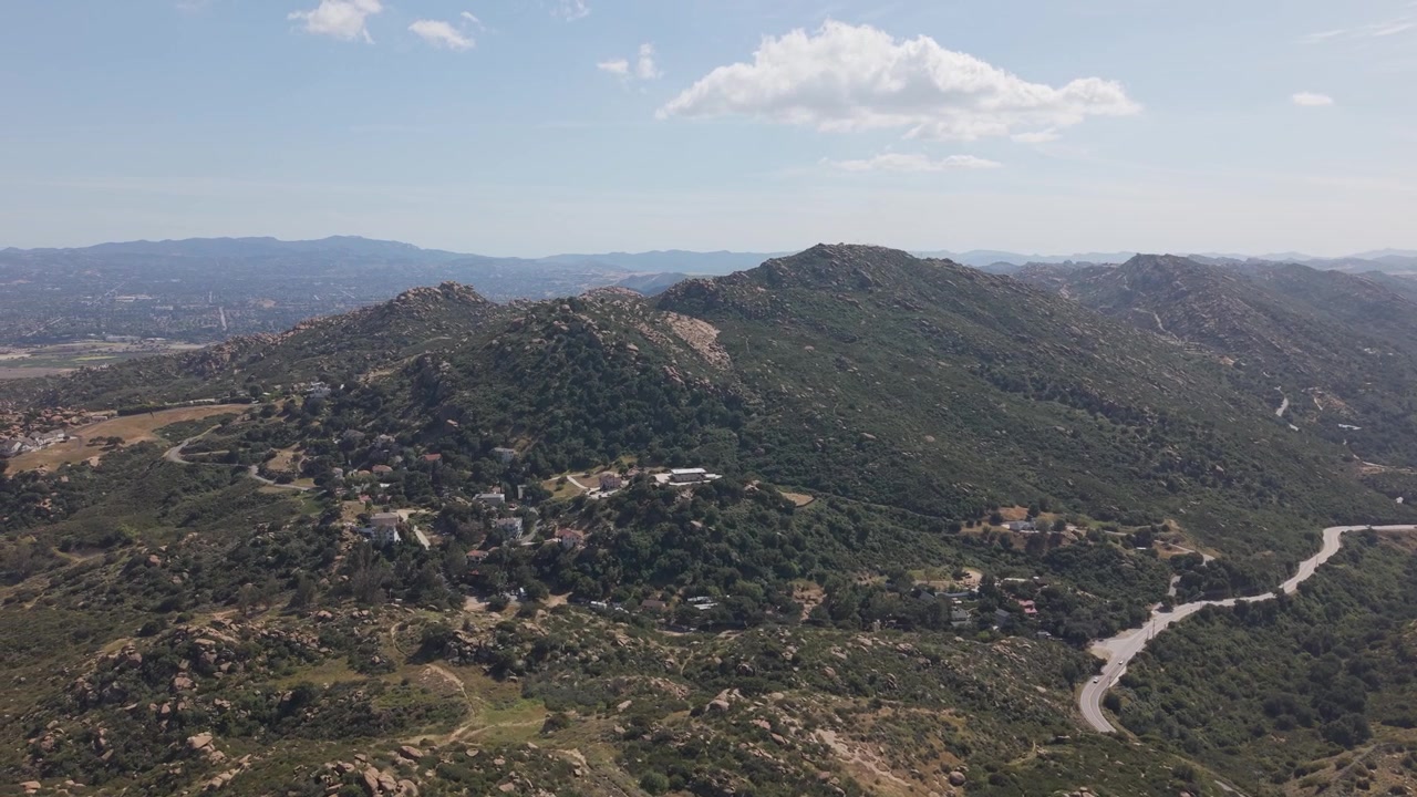 Paesaggio montano panoramico del Parco Storico Statale di Santa Susana Pass che si affaccia sulla Valle di San Fernando, California, con strade tortuose attraverso un terreno collinare arido sotto un cielo azzurro, USA. Panoramica aerea