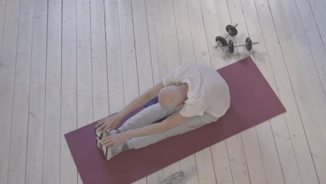 old man stretching and exercising on yoga mat at home 2