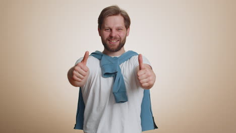 happy young man raises thumbs up agrees or gives positive reply recommends advertisement likes good